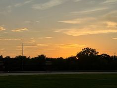 the sun is setting over some trees and grass