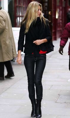 a woman walking down the street wearing black boots and a jacket with red linings