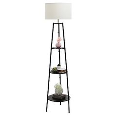 a black metal shelf with a lamp on top and a white shade over the top