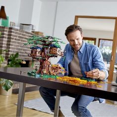 a man sitting at a table with a lego tree