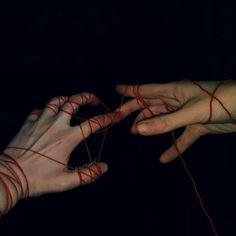 two hands with red string attached to each other