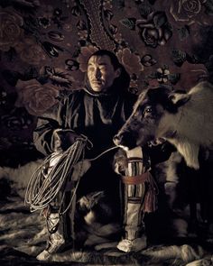 a man sitting next to two animals in front of a wall