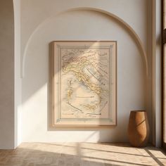 a framed map hangs on the wall next to a vase