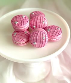 pink macaroons are sitting on a white plate