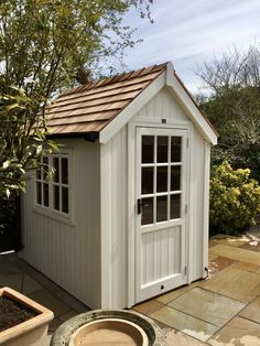 a small white shed sitting next to a potted plant