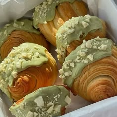 several pastries with green frosting in a white box