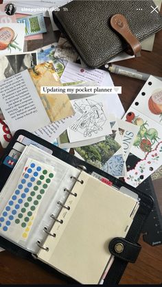 an open pocket planner sitting on top of a wooden table next to papers and pencils