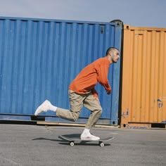 a man riding a skateboard down the middle of a street next to shipping containers