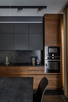 a modern kitchen with black counter tops and wooden cabinetry, along with stainless steel appliances