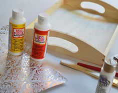 some crafting supplies are laying out on a white tablecloth with gold stencils