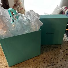 two green boxes filled with items on top of a marble countertop next to a christmas tree