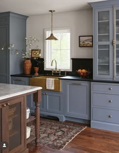 a kitchen with blue cabinets and an island in the middle is decorated with gold accents