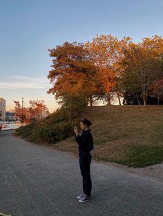 a woman standing on the side of a road taking a photo