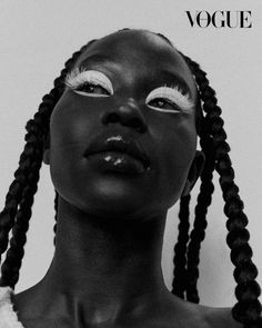 a black and white photo of a woman with braids on her head, wearing eyeliners