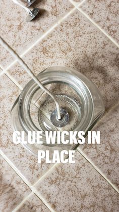 a glass water bottle sitting on top of a tile floor next to a faucet