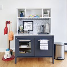 a kitchen area with various items on top of the cabinets and below it is a silver trash can