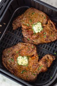 three steaks with butter and parsley in a grill pan