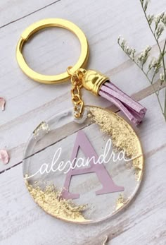 a gold keychain with the word alexandria on it and a purple tassel