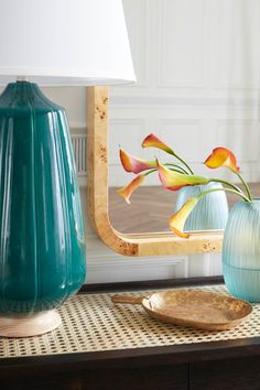 two vases with flowers in them sit on a coffee table next to a mirror