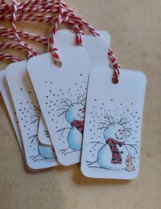 three tags with snowmen on them hanging from twine