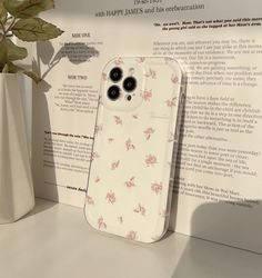 an iphone case sitting on top of a table next to a vase with flowers in it