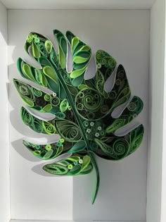 a paper sculpture of a green leaf in a white box