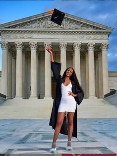 a woman in a white dress and black graduation cap is throwing her hat into the air