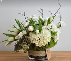 a vase filled with white flowers on top of a wooden table