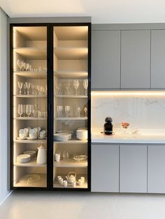 a kitchen with glass doors and shelves filled with dishes, cups and glasses on the counter