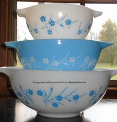 three blue and white bowls stacked on top of each other in front of a window