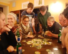 a group of people sitting around a wooden table with beer bottles on top of it