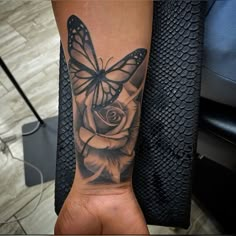 a black and white tattoo with a butterfly on it's arm next to a rose