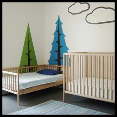 a baby's room with two cribs and trees painted on the wall