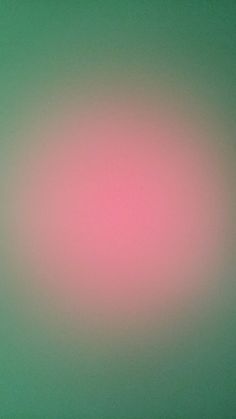 a blurry image of a pink and green background with the light reflecting on it's surface