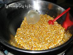 corn being cooked in a bowl with a red spoon