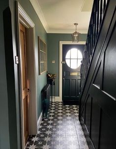 a hallway with black and white tile flooring next to an open door on the other side