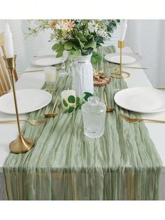 the table is set with white plates and gold place settings, flowers in a vase