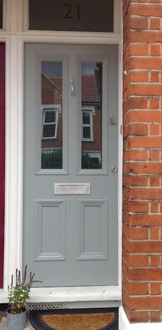 the front door is painted gray and has two potted plants on the side walk