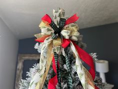 a decorated christmas tree with red, white and green ribbons on it's top