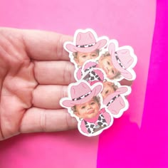 a hand holding a pink sticker with pictures of children in cowboy hats