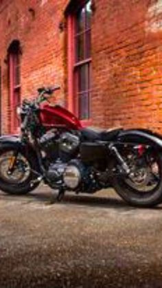 a red motorcycle parked in front of a brick building