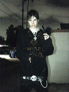 a young man standing on the sidewalk holding a knife and fork in his hand while looking at the camera