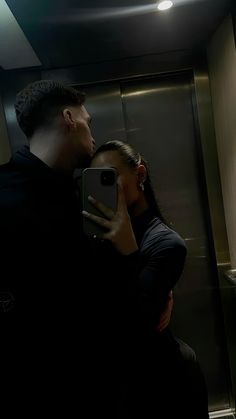 a man and woman are taking a selfie in the mirror while standing next to each other