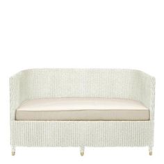 a white wicker couch with a tan cushion on it's backrest and legs