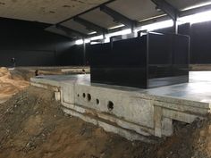 there are two black boxes sitting on top of a pile of dirt in an empty building