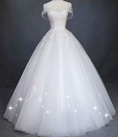 a white wedding dress on display in front of a gray background with stars and sparkles