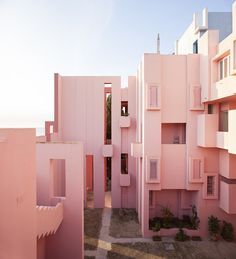 pink building with multiple balconies and windows on each floor in front of other buildings