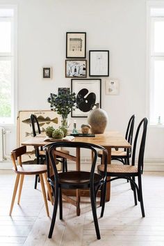 a dining room table with chairs and pictures on the wall