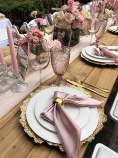 the table is set with pink and white plates, silverware, and napkins