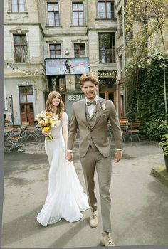 a bride and groom walking in front of an old building